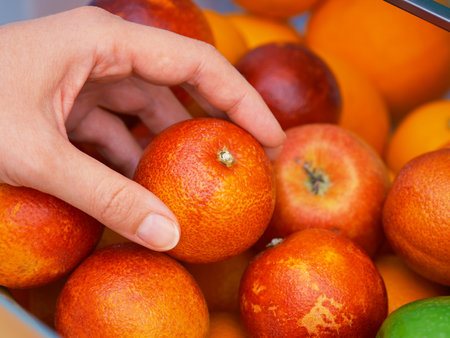 A woman getting a cara cara orange from a fridge compartment. Close up.の写真素材
