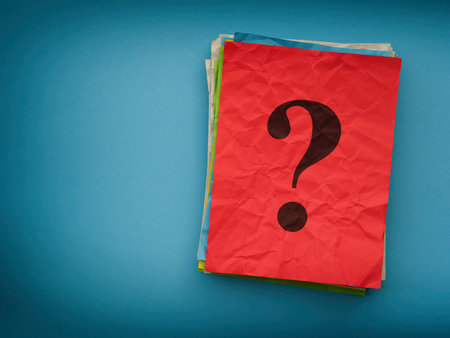 A stack of colorful paper notes with a question mark on them on a blue background. Close up.の写真素材