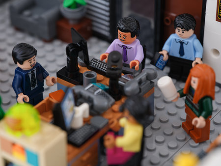 Tambov, Russian Federation - June 23, 2023 A Lego businessman minifigure working on a computer in an office with business people minifigures standing nearby. Close up.のeditorial素材
