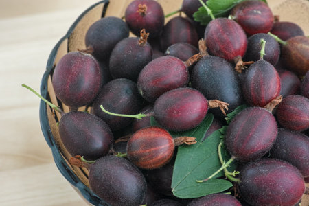 Red gooseberries in a glass bowl on a wooden surface. Close up.の写真素材