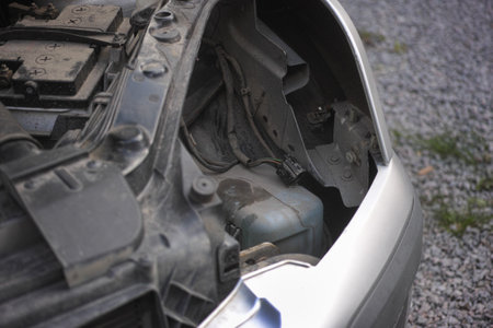 A car with a removed headlight and an open hood standing on a rocky driveway. Close up.の写真素材