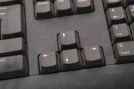 The arrow keys of a black dusty computer keyboard. Close up.の写真素材