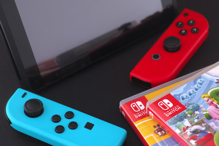Tambov, Russian Federation - December 01, 2023 A Nintendo Switch console with detached joy-cons lying near a stack of Nintendo Switch games in boxes.のeditorial素材