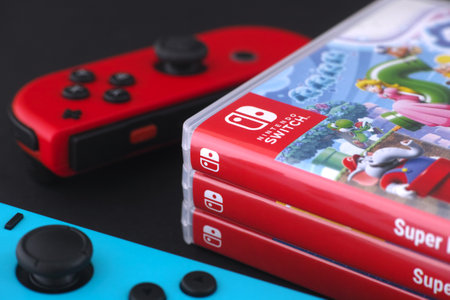 Tambov, Russian Federation - December 01, 2023 A red and a blue  Nintendo Switch joy-con lying near a stack of Nintendo Switch games in boxes.のeditorial素材