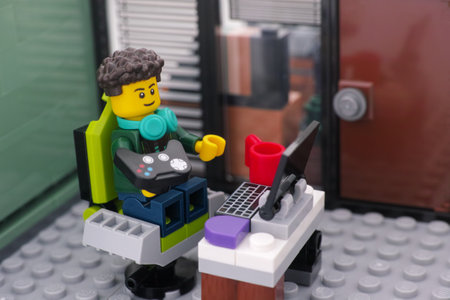 Tambov, Russian Federation - December 25, 2023 A Lego video game player minifigure with a gamepad sitting in a gaming chair and playing video games on a PC.のeditorial素材