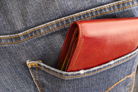 Brown wallet in the jeans back pocket. Close-up.