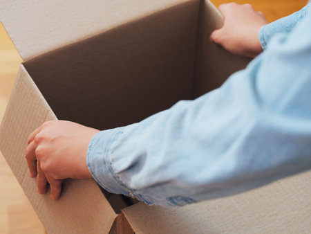 A person opening a cardboard box. Shallow depth of field. Close up.