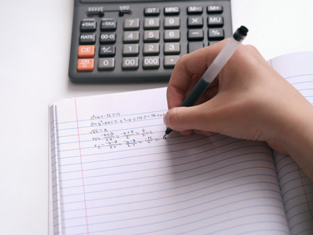 A student doing math in a notebook. Close up.