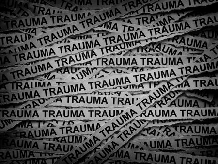 Strips of newspaper with the words Trauma typed on them. Black and white. Close up.