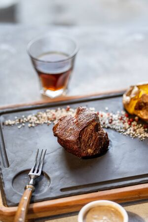 Beef steak with sauce and potato and shot of whiskyの写真素材