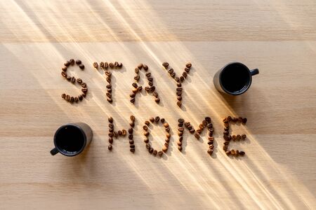 Inscription stay home with coffee beans with cup of coffeeの写真素材