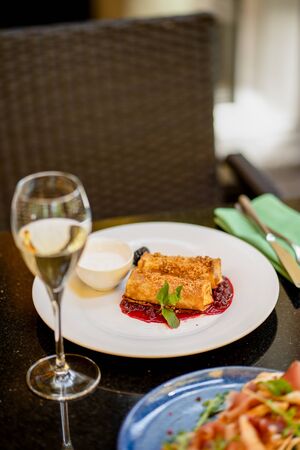 Thin pancakes with jam and glass of wine at terrace bokehの写真素材