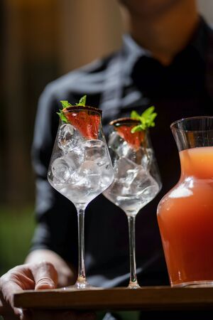 Waiter with Grapefruit lemonade with green and glasses on wooden board terrace bokehの写真素材