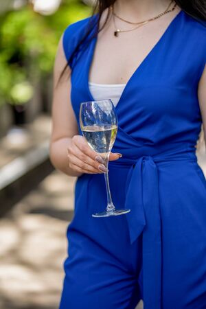 Woman hand and body with glass of white wine on terrace summer bokehの写真素材