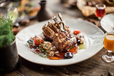 Plate with grilled ribs with sauce haute cuisine on wooden table in sunny daylight restaurantの写真素材