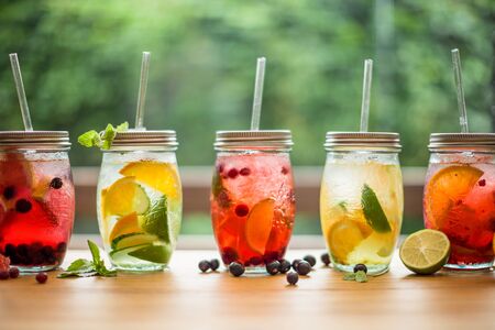 Lemonades on summer spring terrace table with organic fruits on leaf bokeh daylightの写真素材