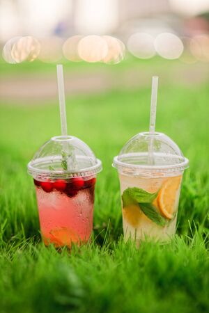 Lemonade with berries grape kiwi orange basil lime on green grass summer spring cafe restaurant daylight street bokehの写真素材