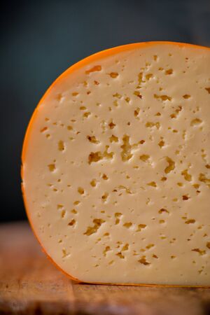 Medium hard cheese gouda edam on wooden board on sunlight table traditional table texture side viewの写真素材