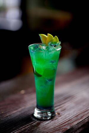 Cocktail with ice berries mint on bar counter daylight side view on bar bokehの写真素材