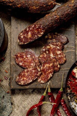 Beef jarky sausage with spices on wooden board with garlic pepper jar wooden texture top viewの写真素材