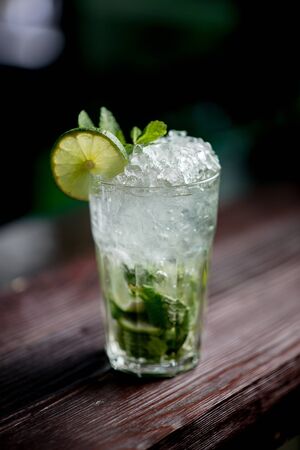 Cocktail with ice berries mint on bar counter daylight side view on barの写真素材