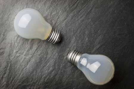 Two light bulbs on a grey background.