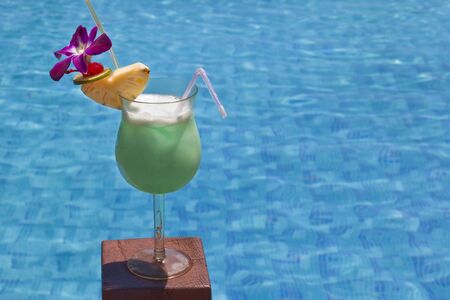 Green cocktail with a swimming pool in the background.の写真素材