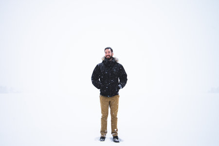 Man in winter clothes standing on the snow covered lake during a Snowfall.の写真素材