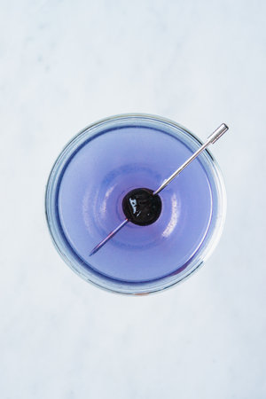 Violet Aviation cocktail with maraschino cherry on white marble background, top viewの写真素材
