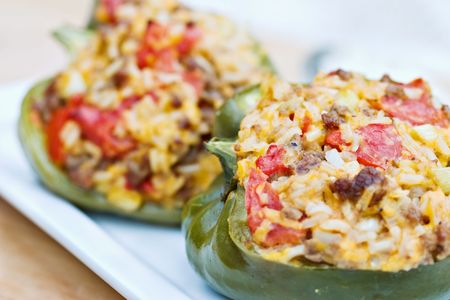 Macro of baked peppers stuffed with turkey burger, rice, tomatoes and cheddar cheese. Shallow DOF with focus on pepper in front. の写真素材