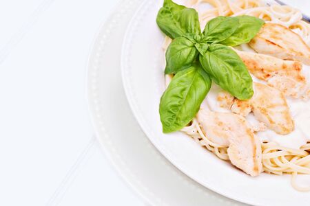 Chicken alfredo with basil on a white beadboard の写真素材