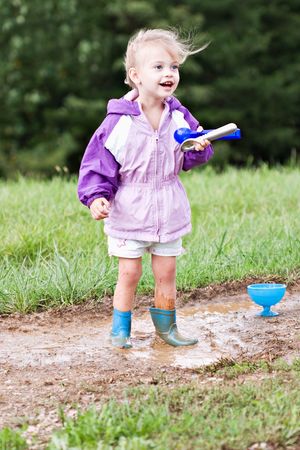 Cute little girl playing in the mud with ice cream scoops.の写真素材