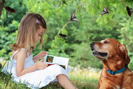 Little girl sits under a tree reading a book about butterflies as her faithful dog sits nearby watching butterflies fly around them. Butterfly, including one in book, are my own photos. の写真素材