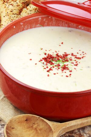 Homemade potato soup garnished with bacon bits and chives and served with Italian herb bread.の写真素材