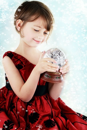 Happy little girl holding a snow globe.の写真素材