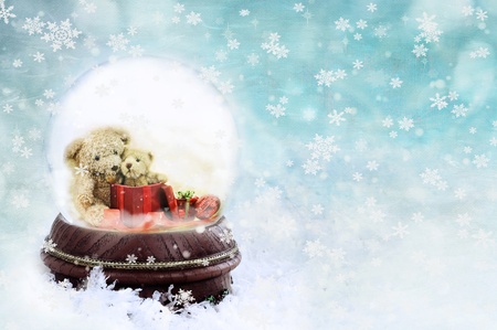 Two adorable little teddies inside of a snow globe against a blue background.の写真素材
