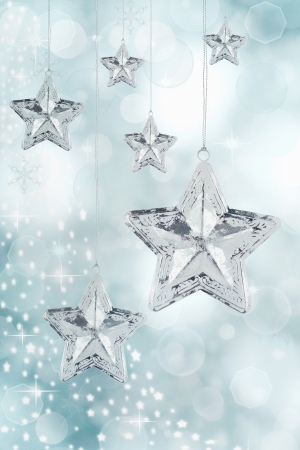 Hanging silver Christmas star ornaments against a festive blue background. の写真素材
