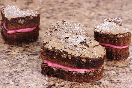 Three delicious heart shaped brownies piped with strawberry or raspberry flavored frosting.の写真素材