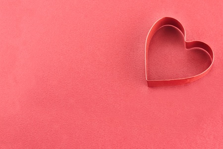 Heart shaped cookie cutter over a red background.の写真素材