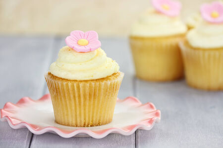 Pretty yellow and pink cupcakes with extreme shallow depth of field with antique dishes.の写真素材