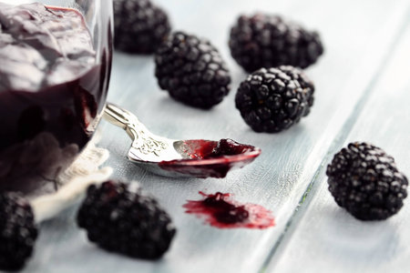 Messy spoon with blackberry jelly on a blue table  Extreme shallow depth of field and selective focus on jelly on spoon の写真素材