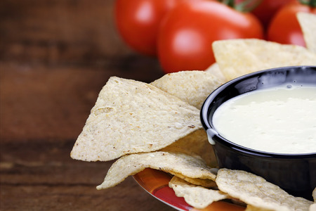 Queso Blanco or White Cheese Sauce with corn tortilla chips and fresh tomatoes. Extreme shallow...