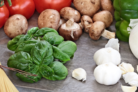 Italian cuisine ingredients of fresh basil leaves, garlic, mushrooms, onions, peppers and fresh tomatoes, Selective focus on basil with extreme shallow depth of field.の写真素材