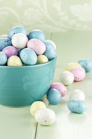 A blue bowl filled with speckled Easter candy eggs. Shallow depth of field.の写真素材