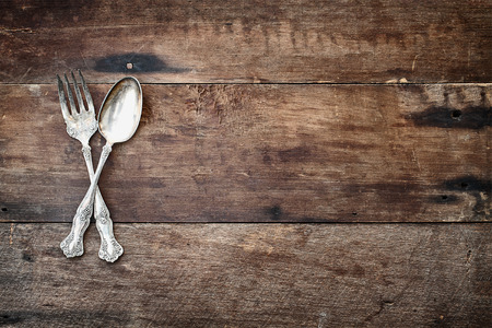 Antique silverware spoon and fork over a rustic old wooden background. Image shot from overhead.の写真素材