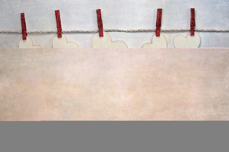 Wooden love Valentine's hearts clipped to cord by red laundry hangers over textured background with copy space available.の写真素材