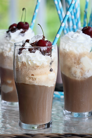 Root beer floats with whipped cream, chocolate sauce, and cherries. Extreme shallow depth of field...