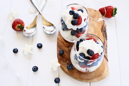 Trifles made with blueberries, strawberries, whipped cream and star shaped pound cake against a white wood background. Perfect for fourth of July. Shallow depth of field with selective focus.の写真素材