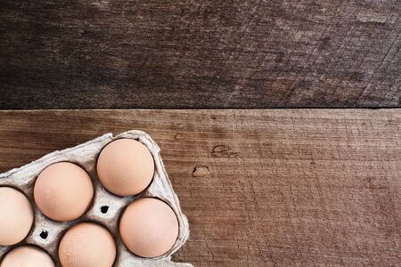 Farm fresh organic brown chicken eggs from free range chickens with in a paper carton over a rustic...
