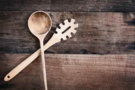 High angle view of a old empty wood spoon and spaghetti fork  over a rustic wooden background. Available copy space for text.の写真素材